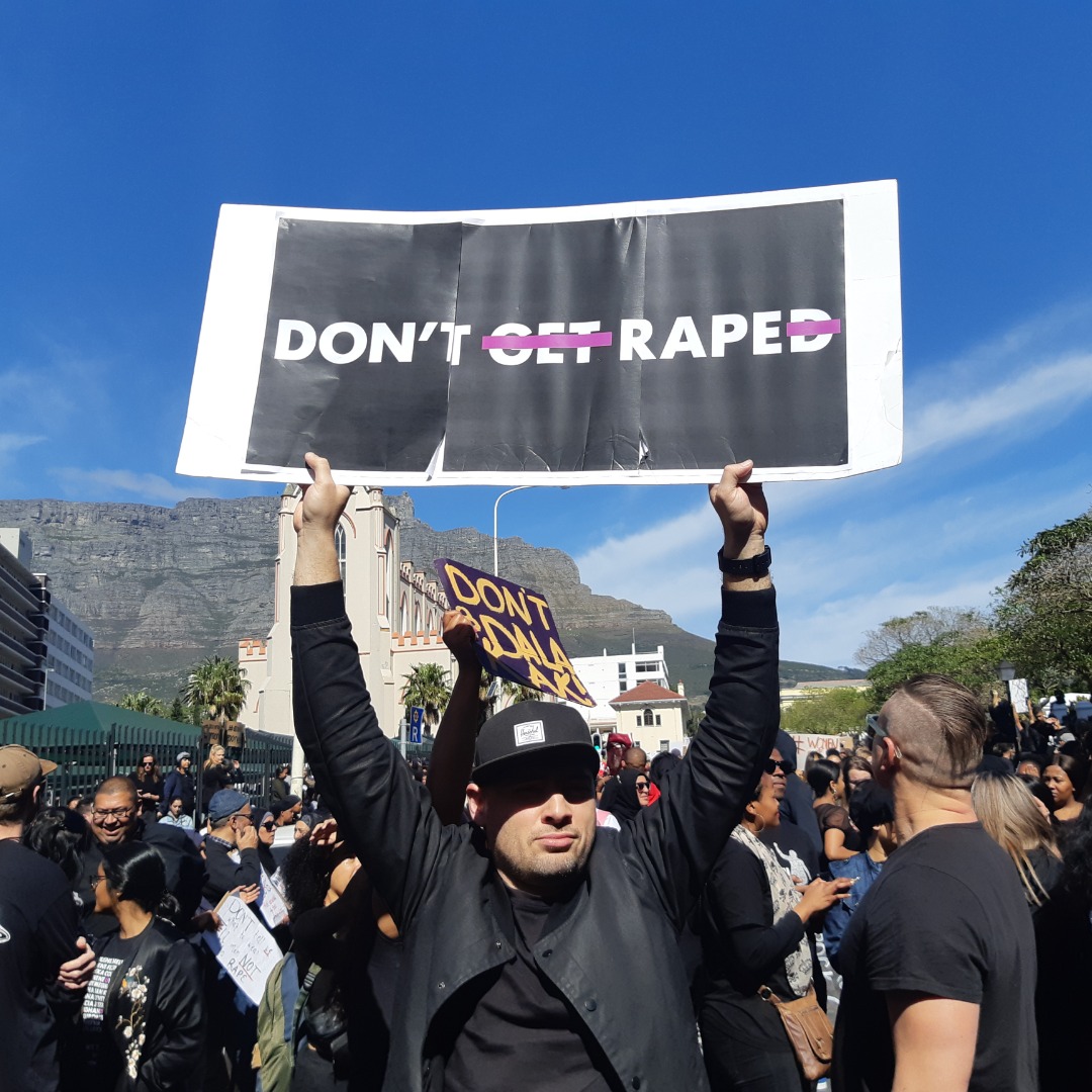 A Man holding a poster that reads "Don't Rape!" instead of "Don't get Raped!"